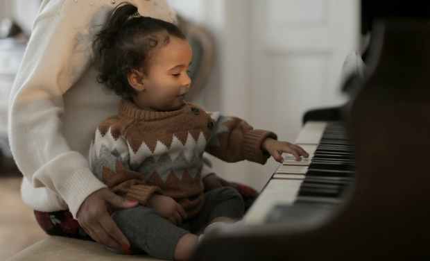 girl in brown sweater playing piano